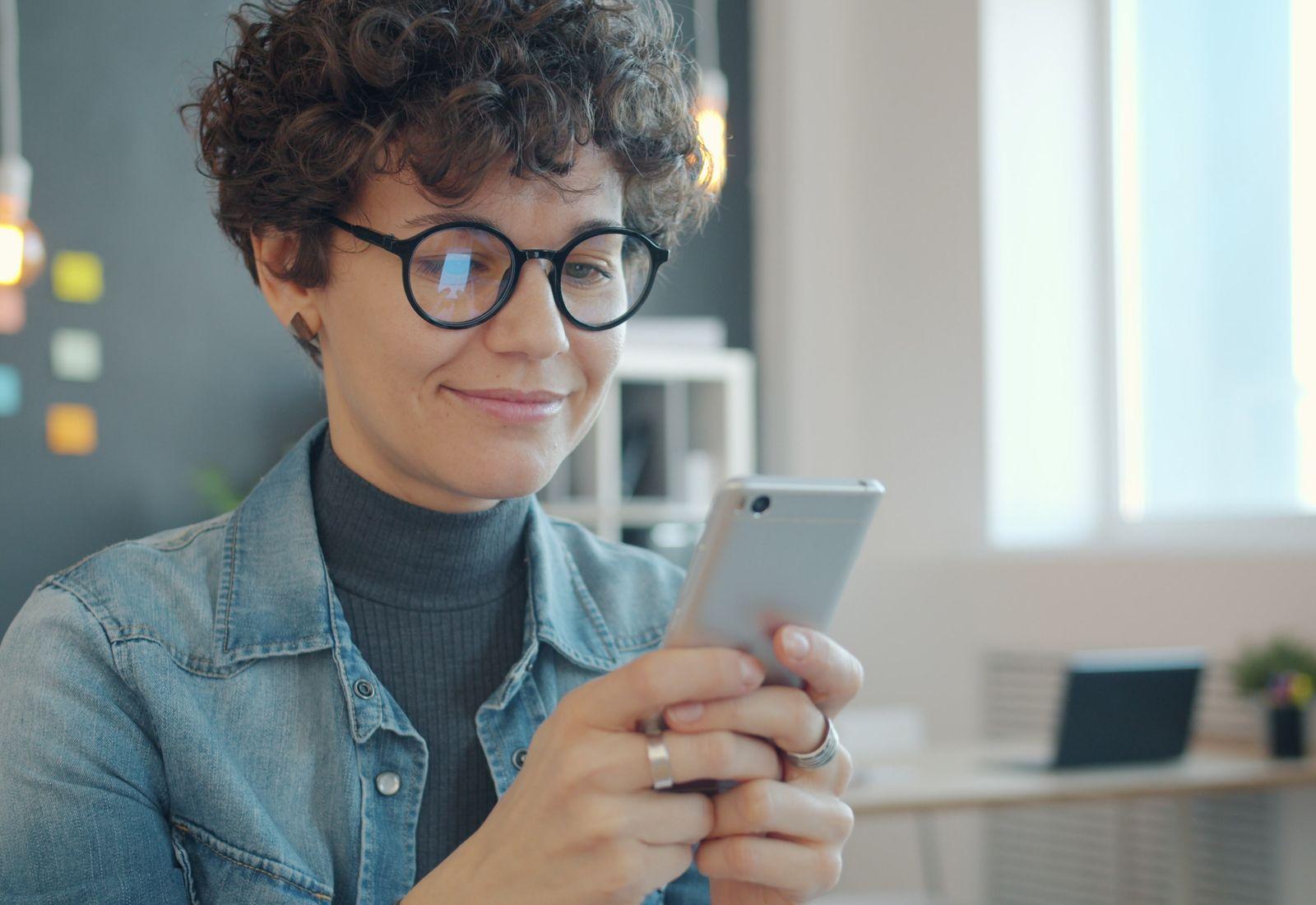 A woman smiles at her phone as a receipt arrives