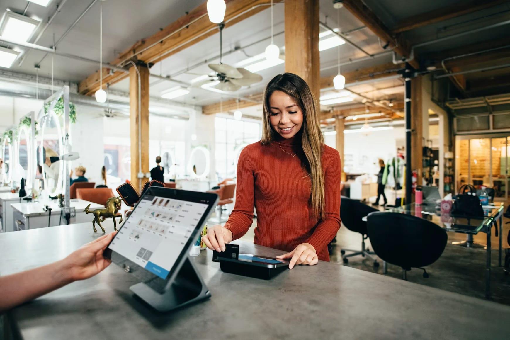 Une cliente paie au comptoir d'un salon avec un terminal de paiement