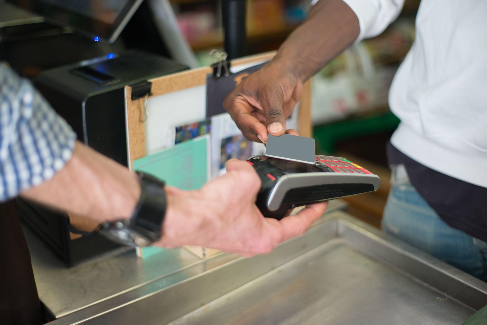 A customer taps a card on a payment terminal at a store counter