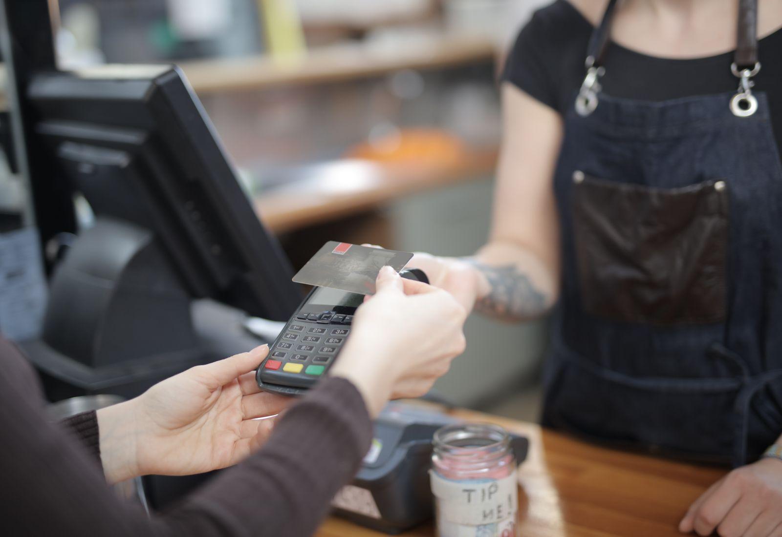 A customer taps a card at a café counter
