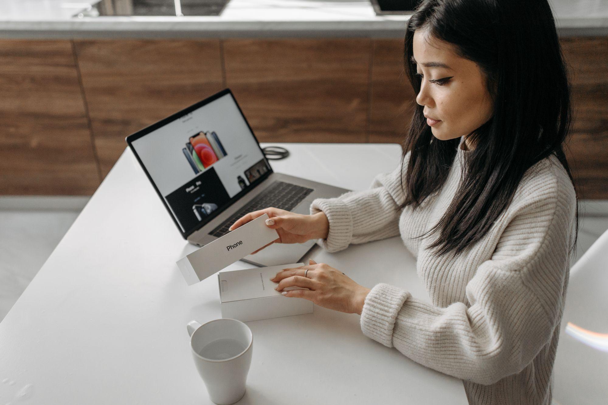A woman unboxes a new phone at her desk