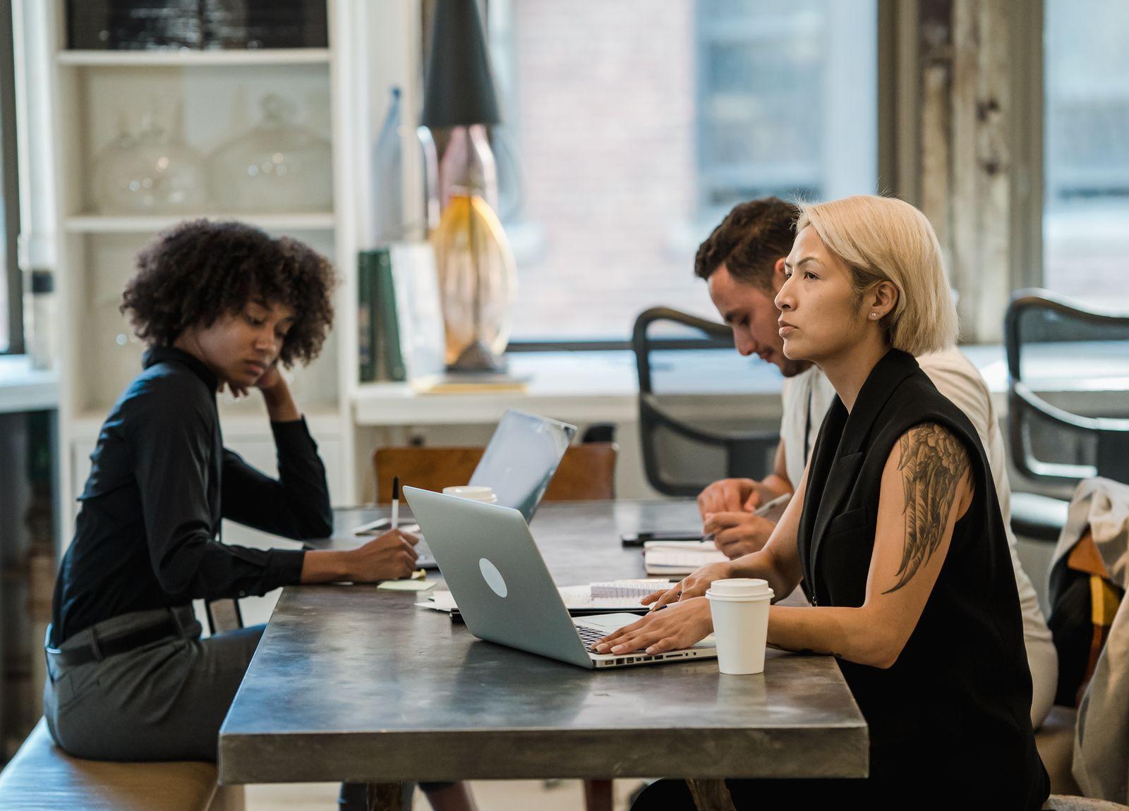 Three colleagues working together at laptops in an office
