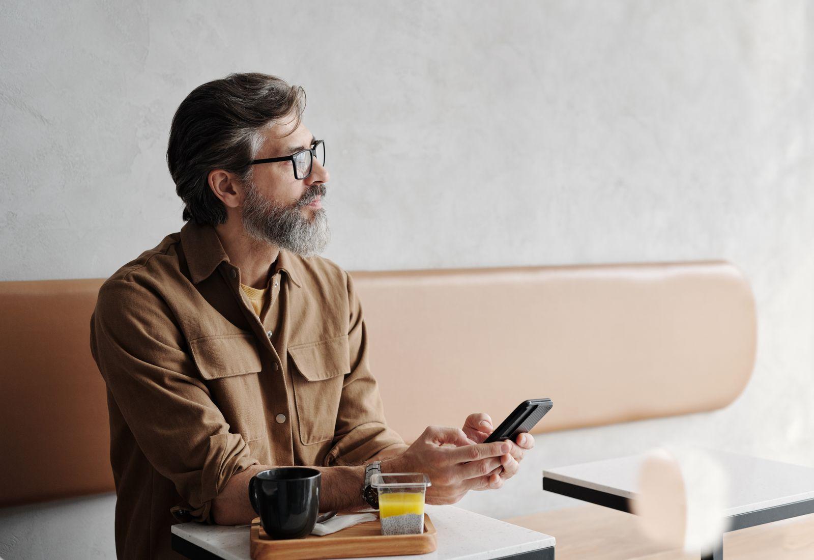 A man at a café looks at a charge on his phone