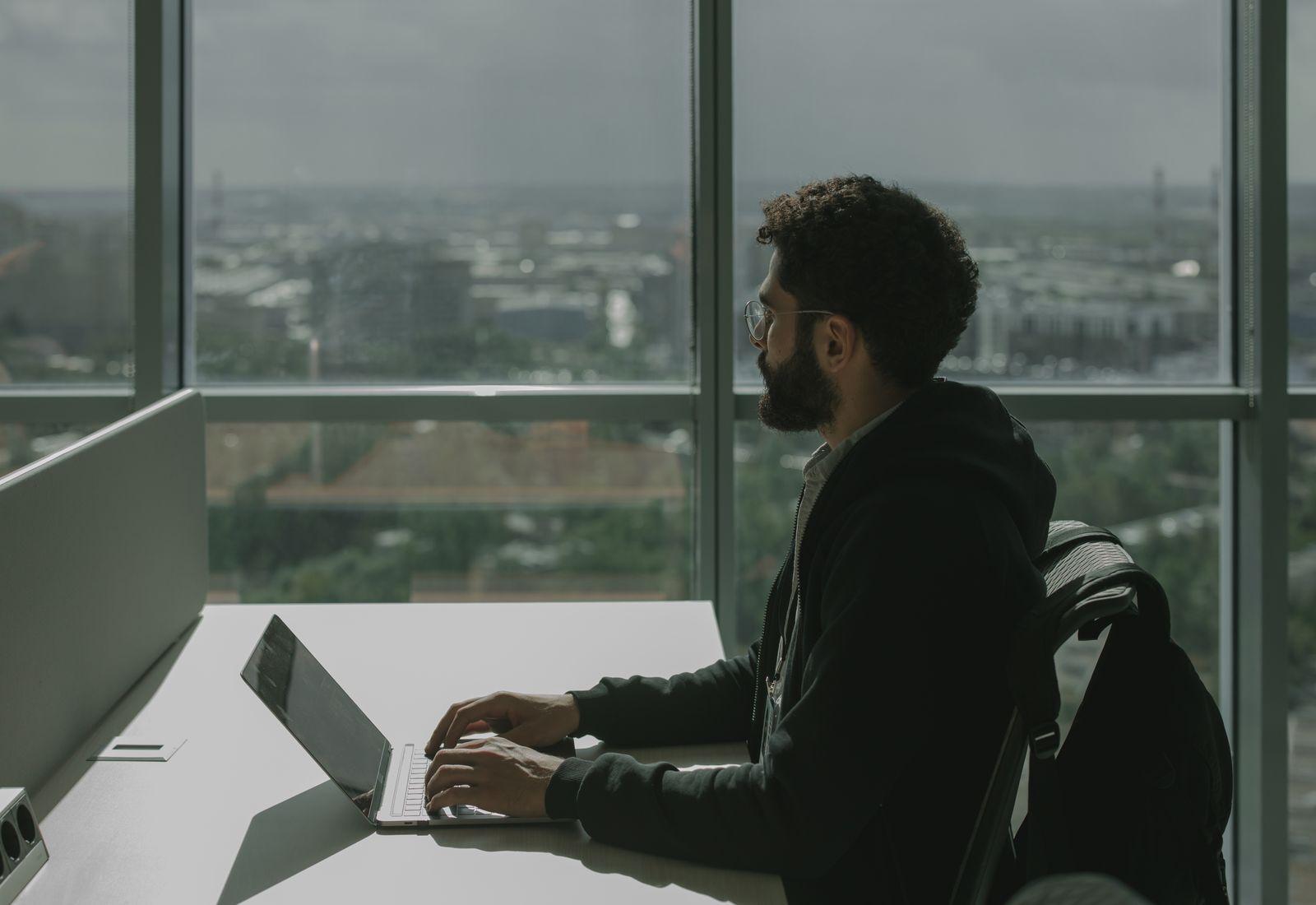 Someone typing on a laptop at a desk by an office window