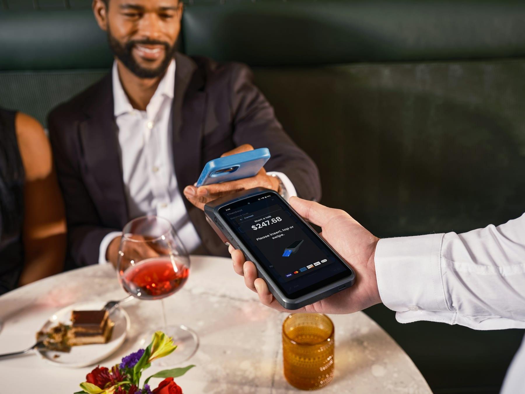 A diner pays by phone at a restaurant table