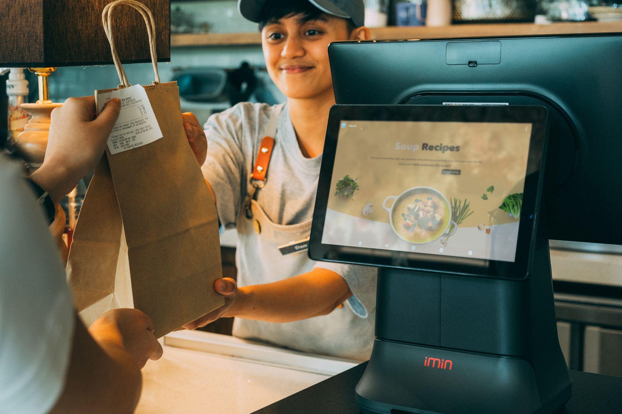 A cashier hands a customer their order at a point of sale
