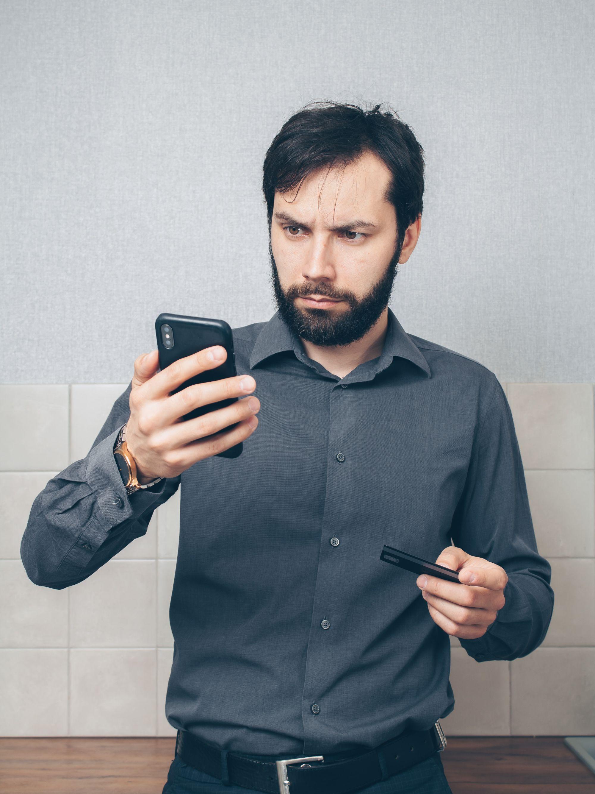 Un homme fronce les sourcils devant un débit sur son téléphone