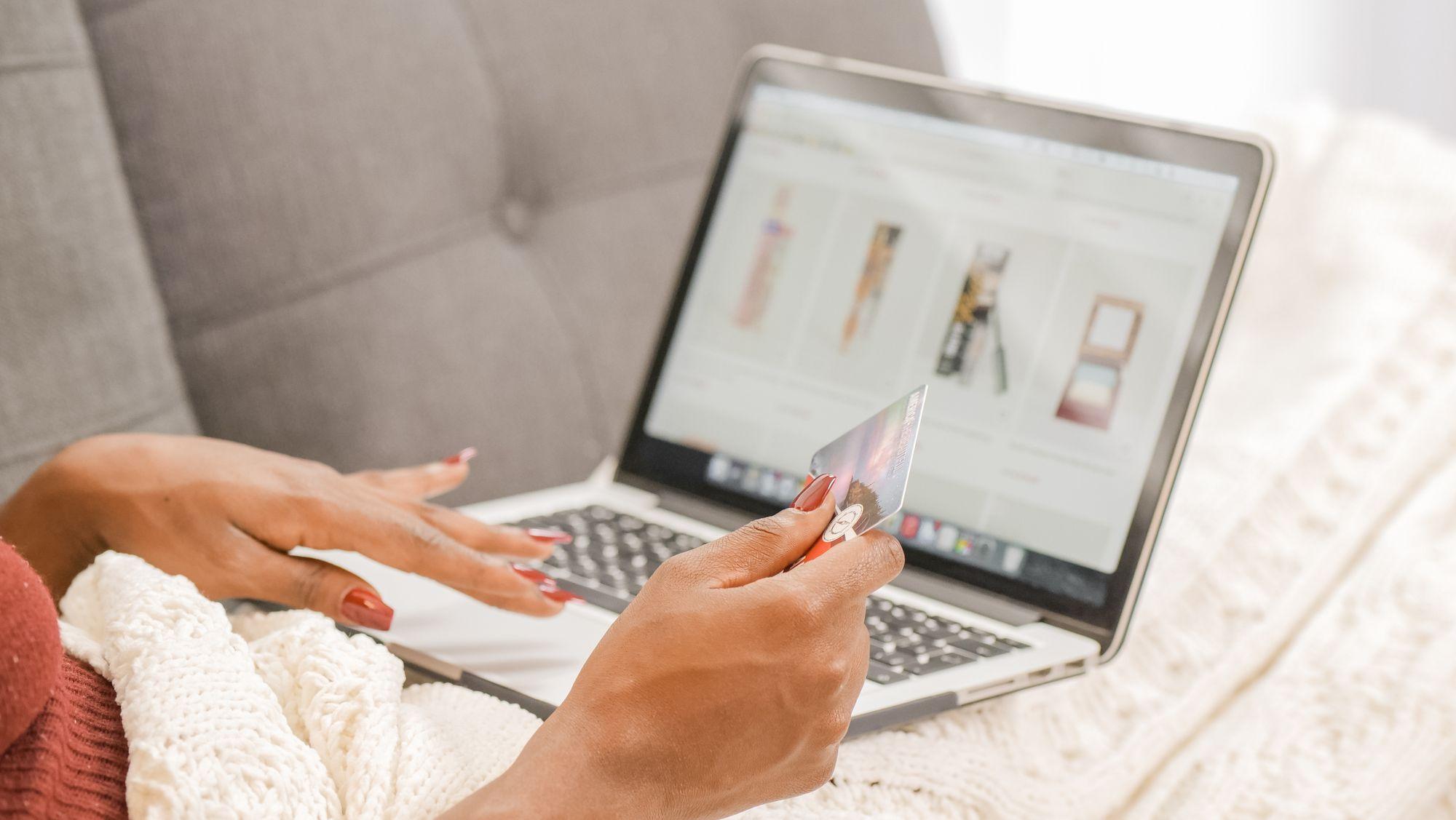 Hands hold a credit card in front of a laptop while shopping online