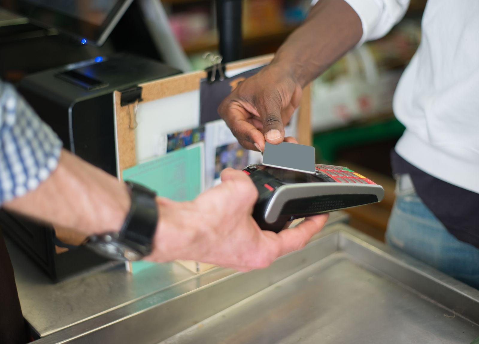 A customer taps a card on a payment terminal at a store counter