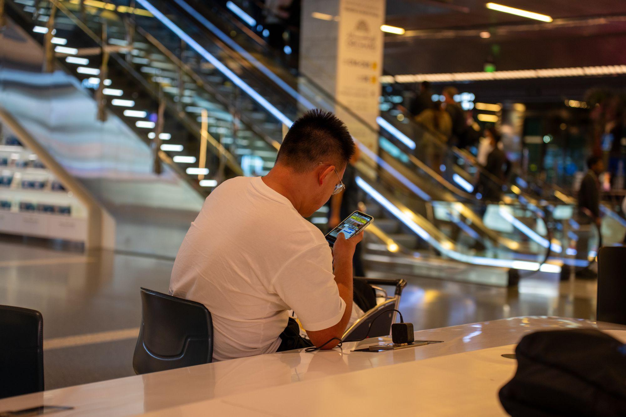 Un voyageur regarde son téléphone dans un terminal d'aéroport