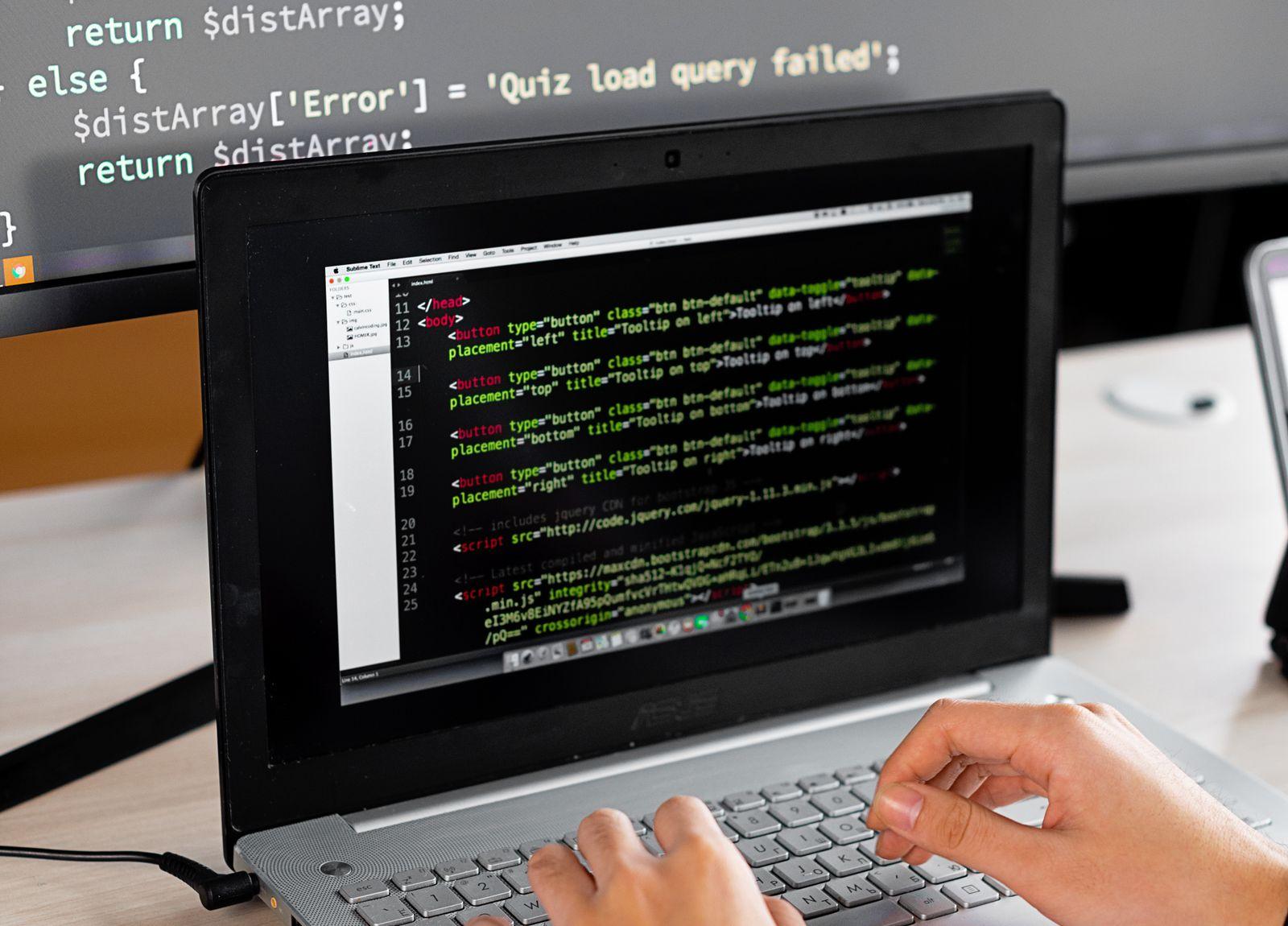 Hands typing code on a laptop at a desk