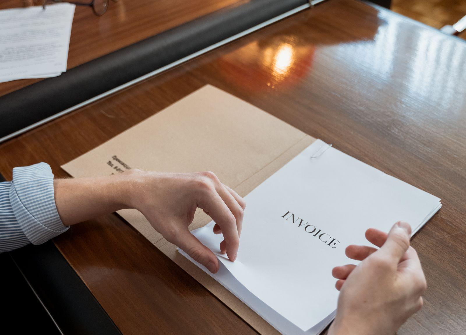 Une personne qui trie une pile de factures à son bureau
