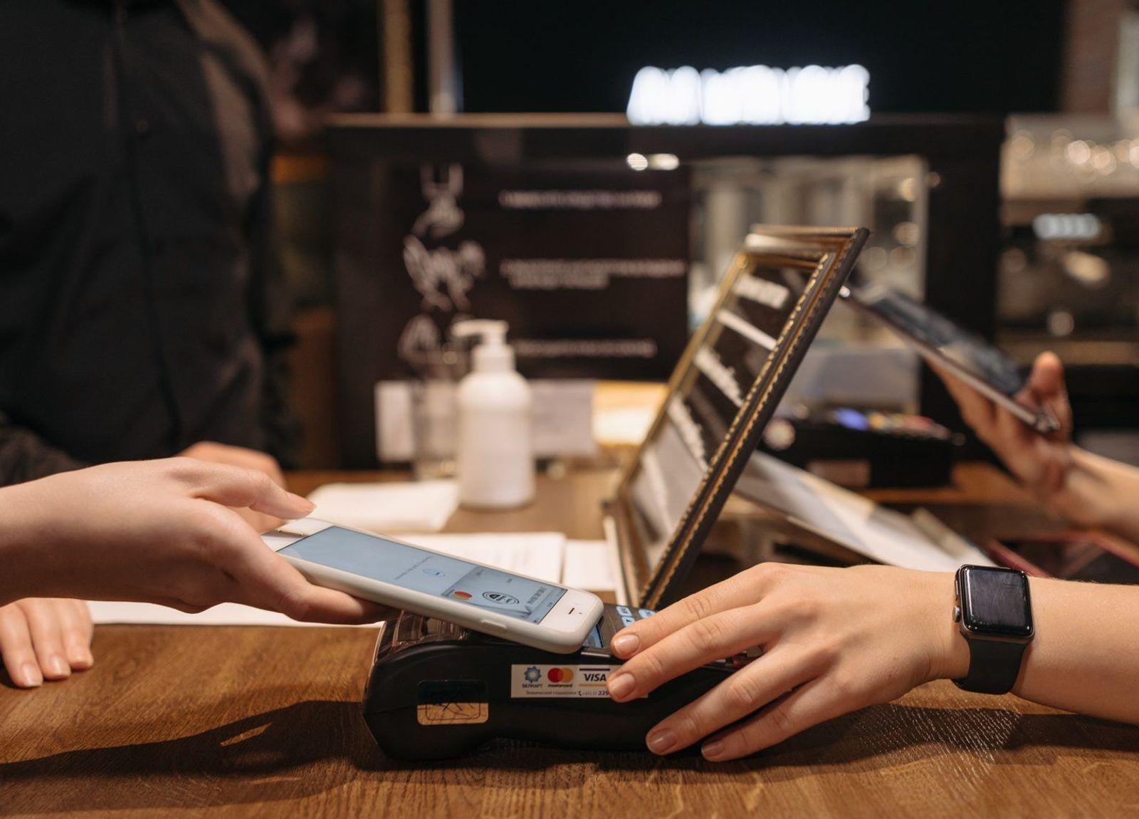 Une cliente qui paie avec son téléphone au comptoir d'un café