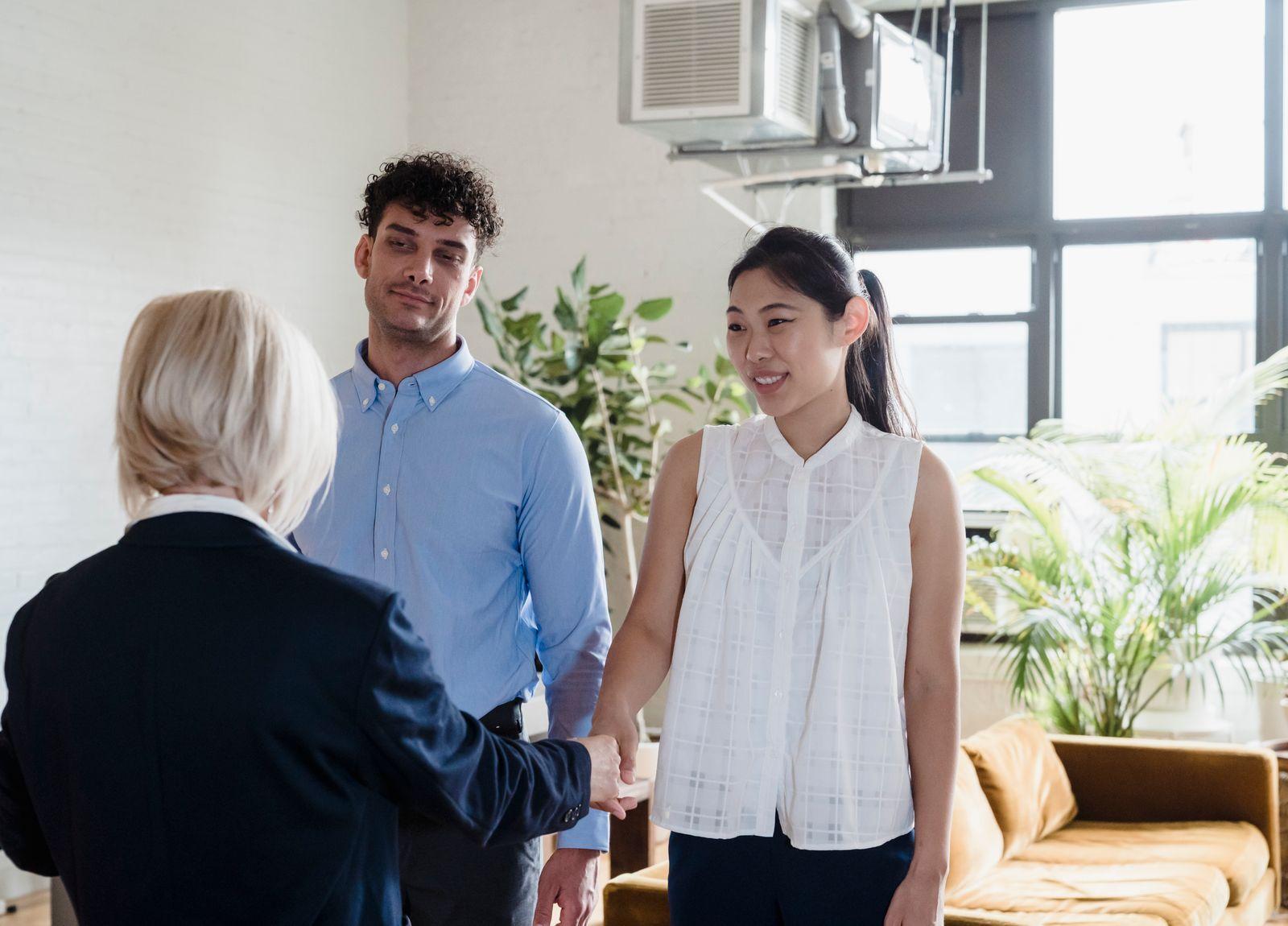 Une agente qui serre la main d'un couple dans son nouvel appartement